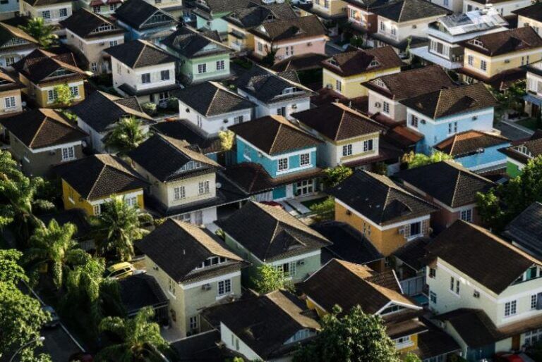 Linear housing area. Brown roofs and pastel bodies of the houses with a few trees around.